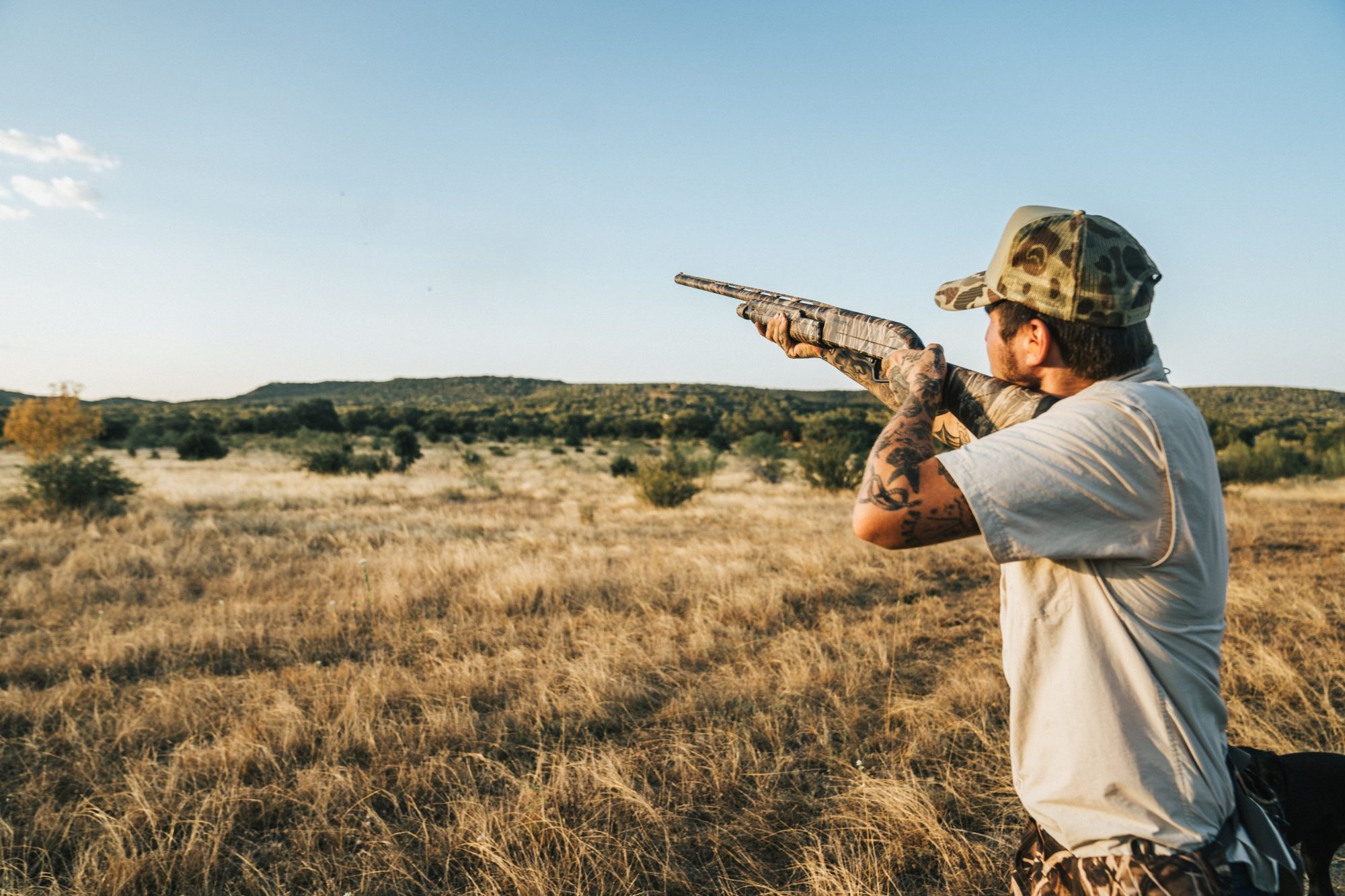 A hunter swinging on a dove over native grass in Texas