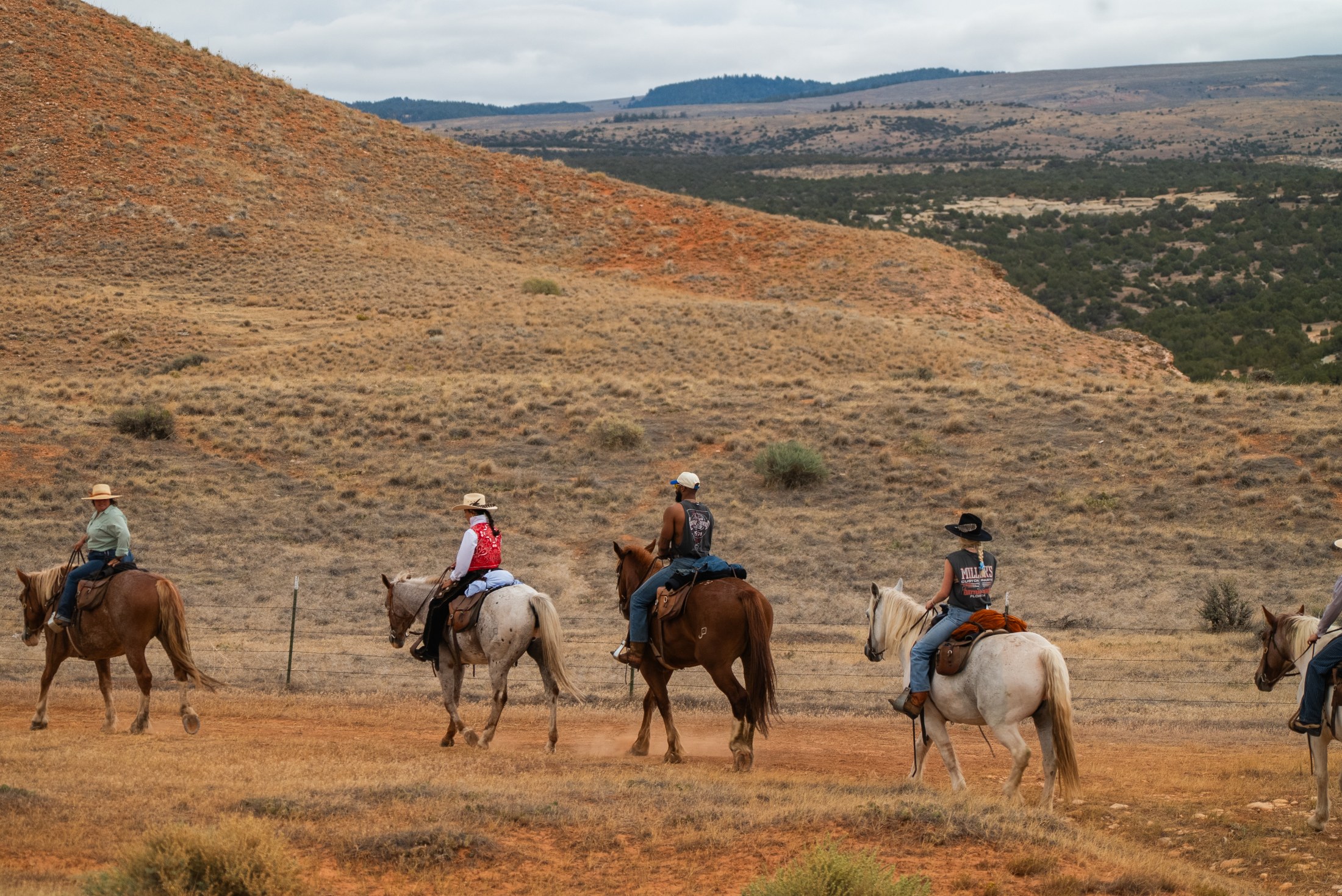Riders crossing the red hills of Paintrock Canyon Ranch, Wyoming