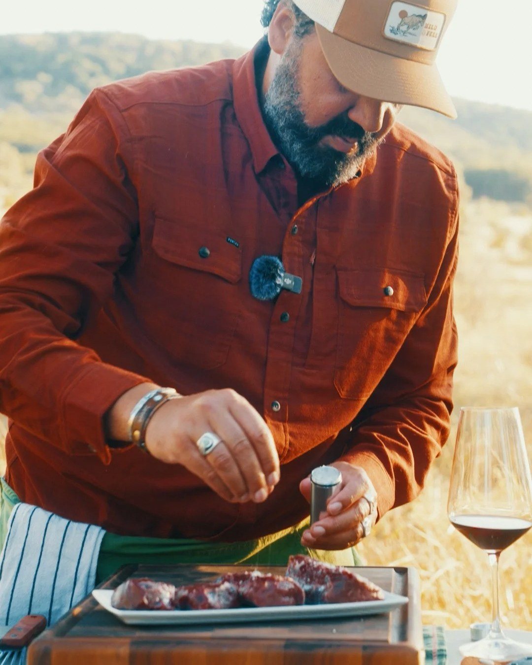 Josh Crumpton seasoning wild game beside a glass of red wine